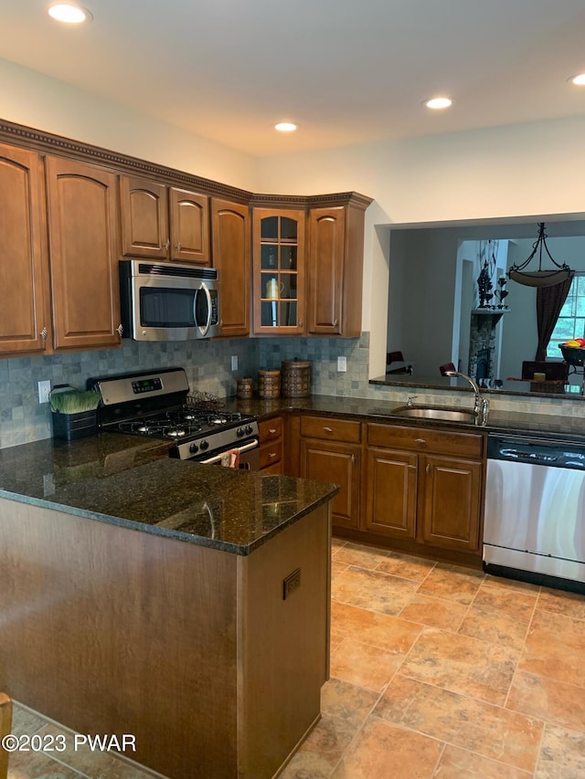 kitchen with sink, backsplash, dark stone countertops, kitchen peninsula, and appliances with stainless steel finishes