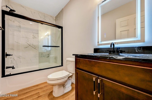 full bathroom featuring combined bath / shower with glass door, hardwood / wood-style floors, vanity, and toilet