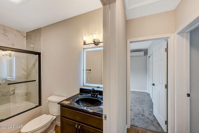 full bathroom with an AC wall unit, shower / bath combination with glass door, vanity, and toilet