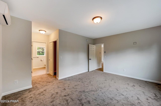 spare room featuring light colored carpet and a wall unit AC