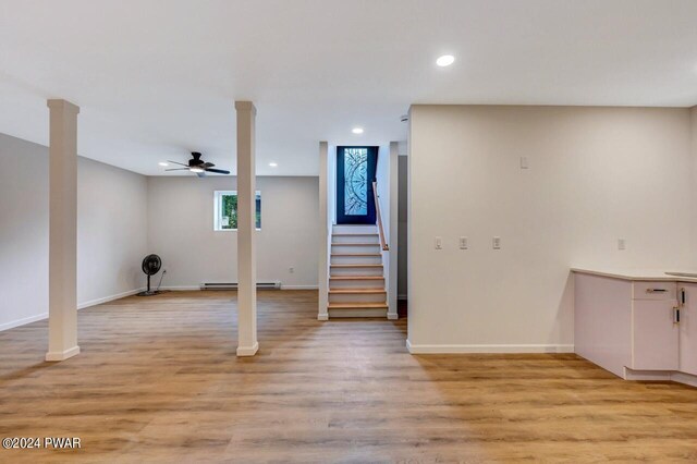 basement featuring light hardwood / wood-style floors, baseboard heating, and ceiling fan