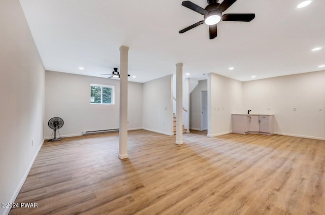 basement with baseboard heating, ceiling fan, and light wood-type flooring