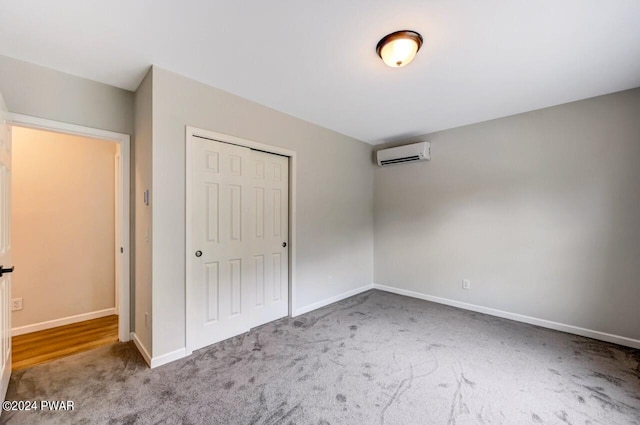 unfurnished bedroom with carpet flooring, a wall unit AC, and a closet