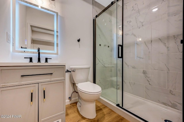 bathroom featuring hardwood / wood-style floors, vanity, toilet, and a shower with shower door