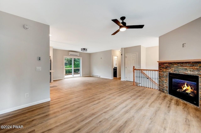 unfurnished living room with light wood-type flooring, baseboard heating, ceiling fan, an AC wall unit, and a fireplace