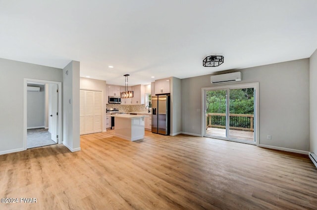 unfurnished living room with light hardwood / wood-style floors, an AC wall unit, and sink