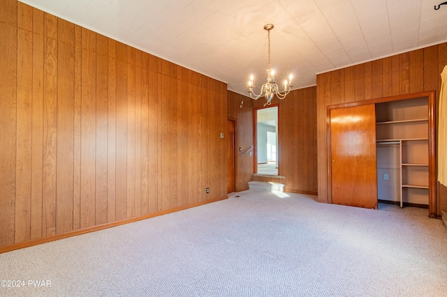 carpeted empty room featuring a chandelier