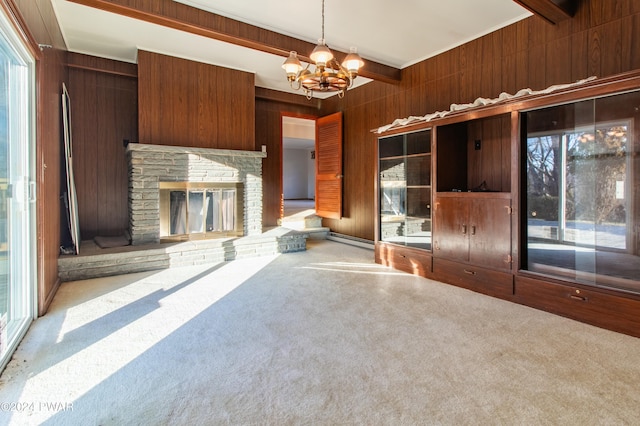 unfurnished living room with beam ceiling, wood walls, carpet floors, and a chandelier