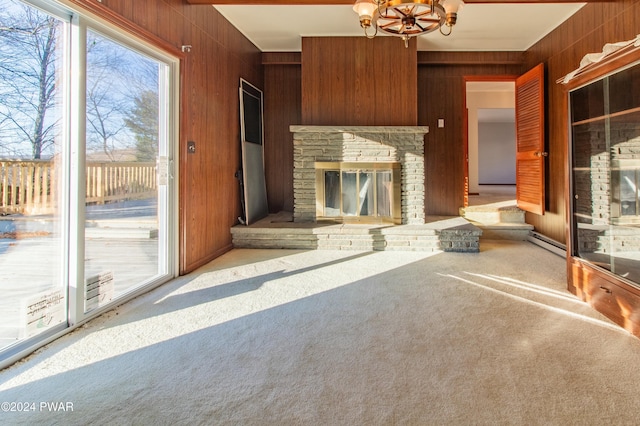 unfurnished living room with wood walls, light carpet, a baseboard radiator, and an inviting chandelier