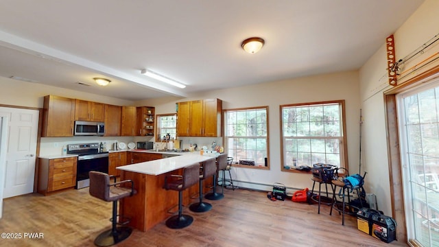 109 Lake Dr, Dingmans Ferry, PA 18328 - kitchen with open shelves, brown cabinets, stainless steel appliances, a peninsula, and a breakfast bar area