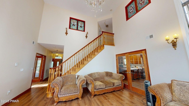 109 Lake Dr, Dingmans Ferry, PA 18328 - living area with stairway, a high ceiling, wood finished floors, a chandelier, and french doors