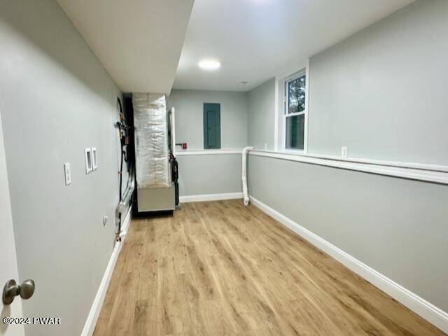 basement with electric panel and light hardwood / wood-style floors