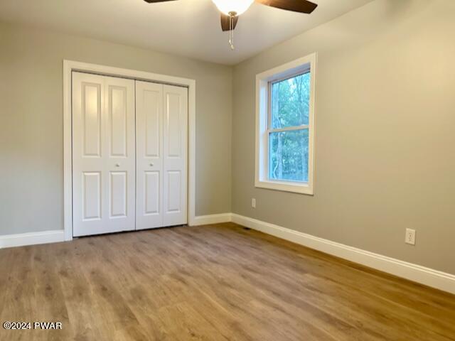 unfurnished bedroom with ceiling fan, a closet, and hardwood / wood-style floors