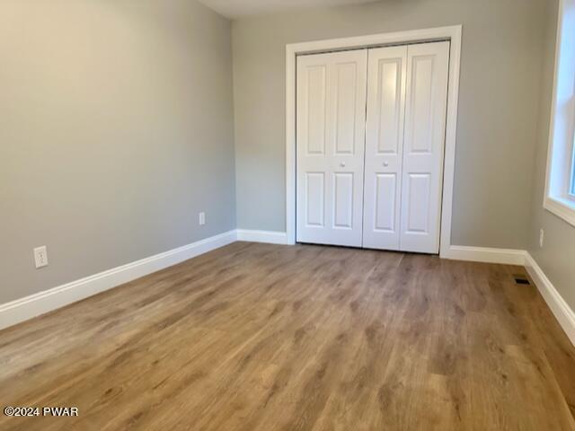 unfurnished bedroom featuring wood-type flooring and a closet