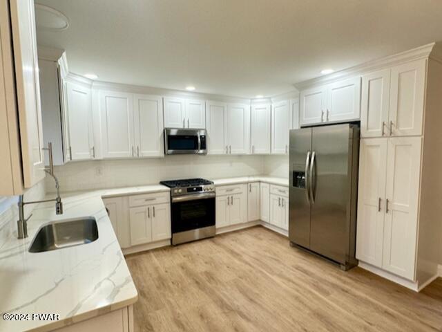 kitchen featuring sink, white cabinets, light hardwood / wood-style flooring, and appliances with stainless steel finishes