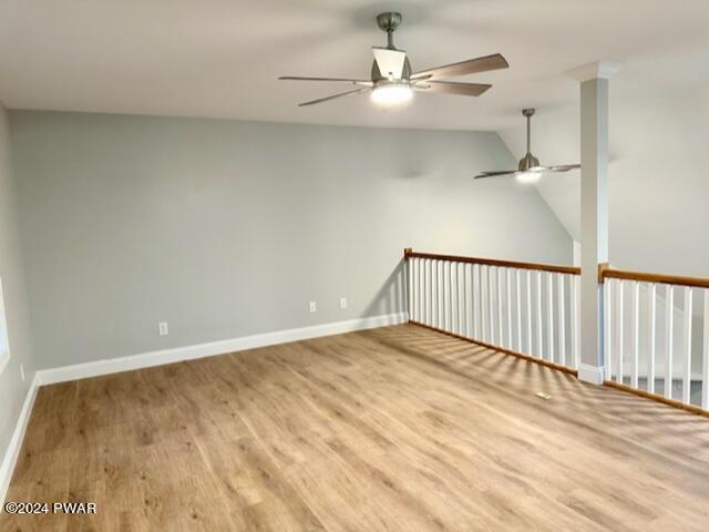 empty room with ceiling fan, vaulted ceiling, and hardwood / wood-style flooring