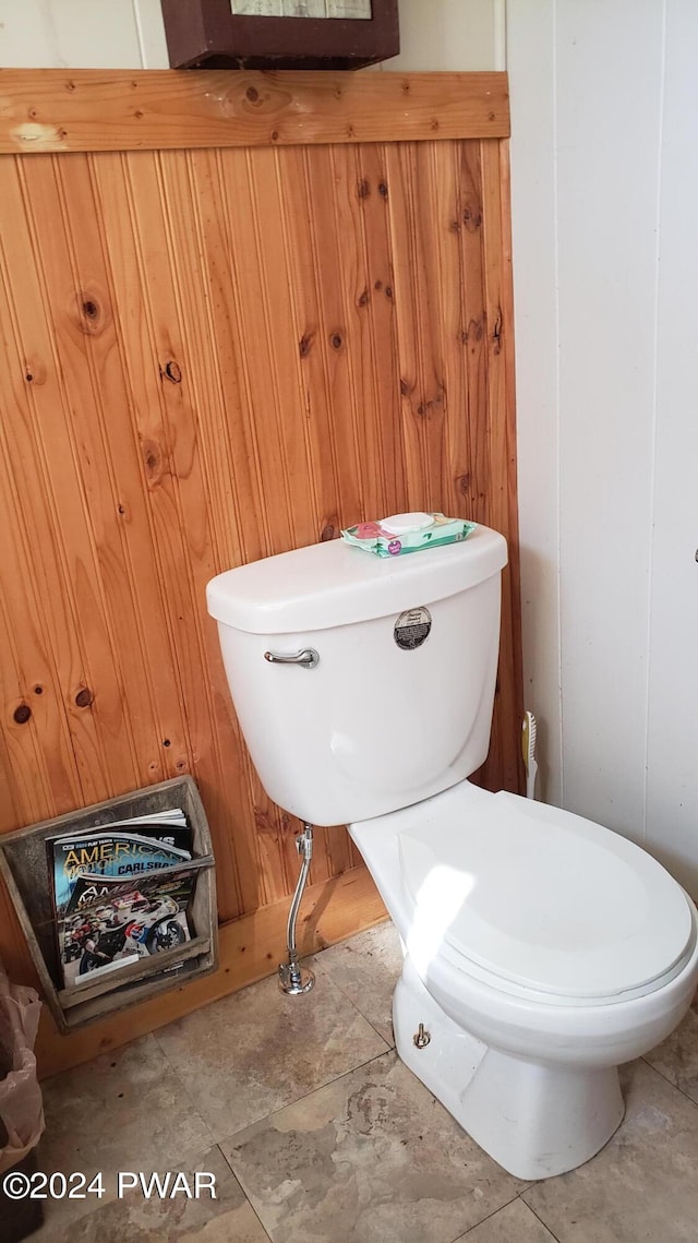 bathroom with toilet and wood walls