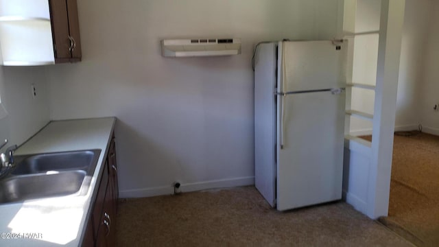 kitchen featuring light carpet, sink, white fridge, and a wall mounted air conditioner