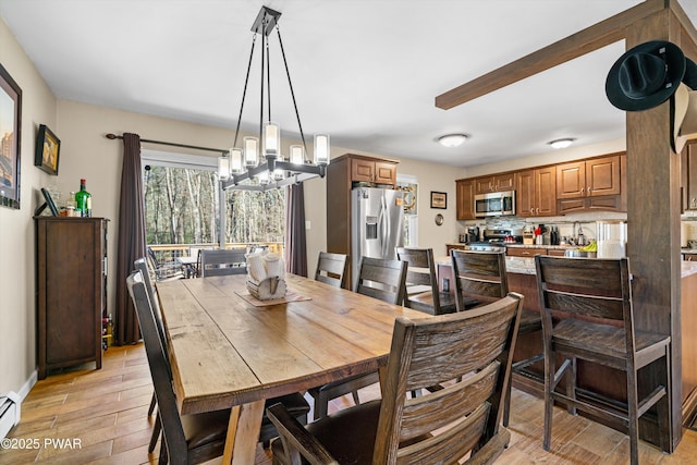 dining area with a chandelier, light wood-style floors, baseboards, and baseboard heating