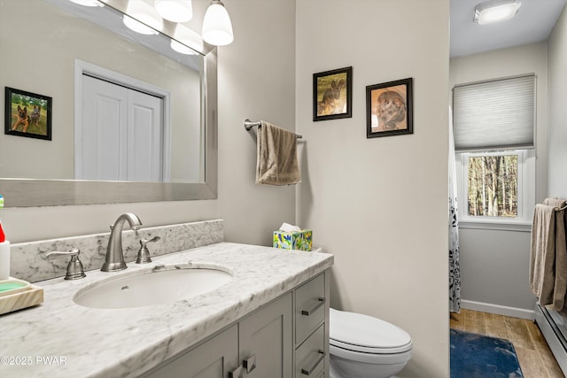 bathroom with vanity, a baseboard heating unit, a shower with curtain, toilet, and wood finished floors