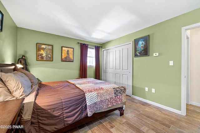 bedroom with wood finished floors, baseboards, and a closet