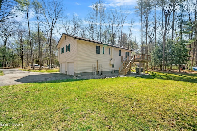 view of side of property with a wooden deck, a lawn, stairs, an attached garage, and driveway