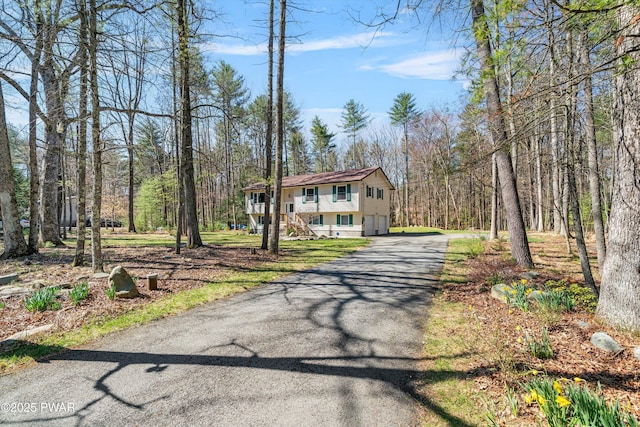 view of front of home with aphalt driveway, a garage, and stairway