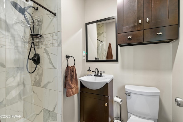 bathroom featuring tiled shower, vanity, and toilet