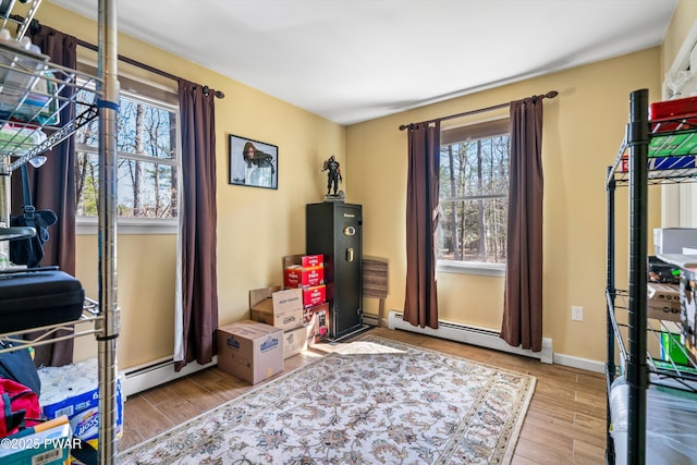 interior space with plenty of natural light, baseboard heating, baseboards, and wood finished floors