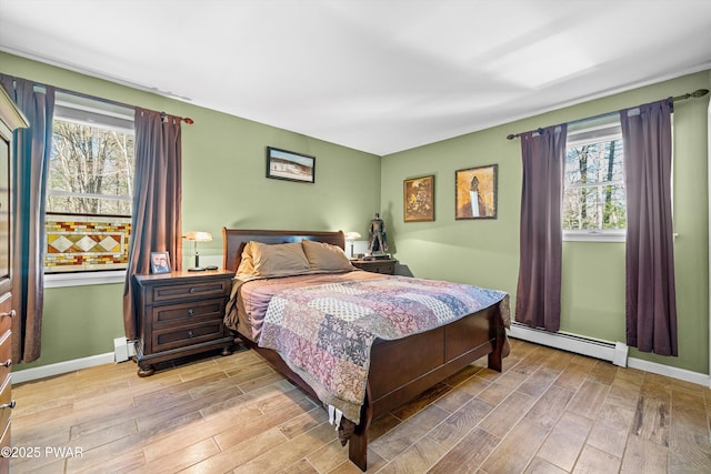 bedroom featuring light wood finished floors, baseboard heating, and baseboards