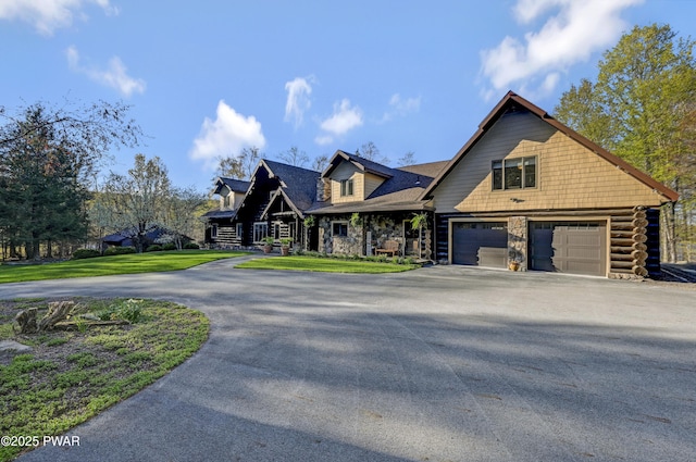 craftsman house featuring a front yard, driveway, stone siding, and a garage