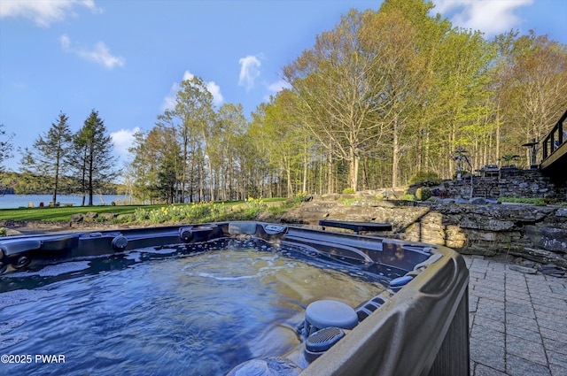 view of swimming pool featuring a hot tub and a water view