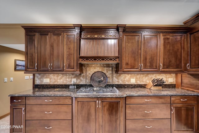 kitchen with dark stone counters, tasteful backsplash, dark brown cabinets, and stainless steel gas stovetop