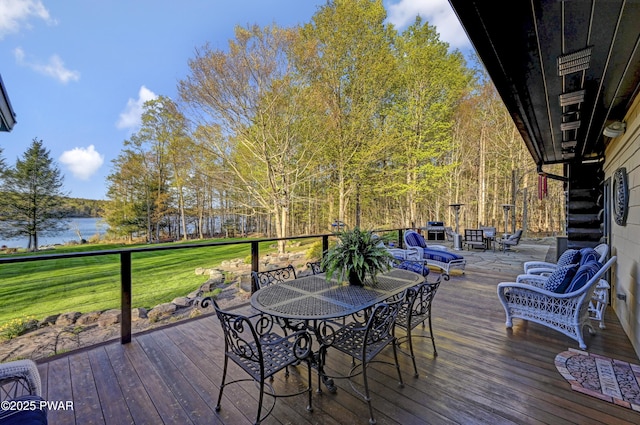 wooden terrace featuring a lawn, a water view, and outdoor dining area