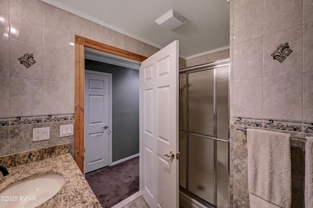 bathroom with visible vents, crown molding, vanity, tile walls, and a stall shower