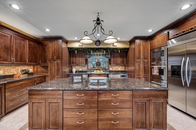 kitchen with backsplash, built in appliances, light tile patterned floors, and a kitchen island