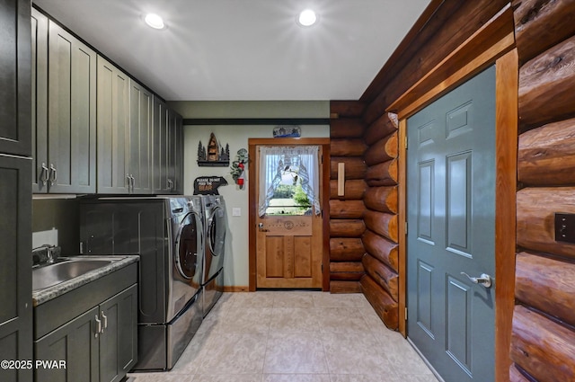 laundry room with washing machine and dryer, cabinet space, a sink, baseboards, and rustic walls