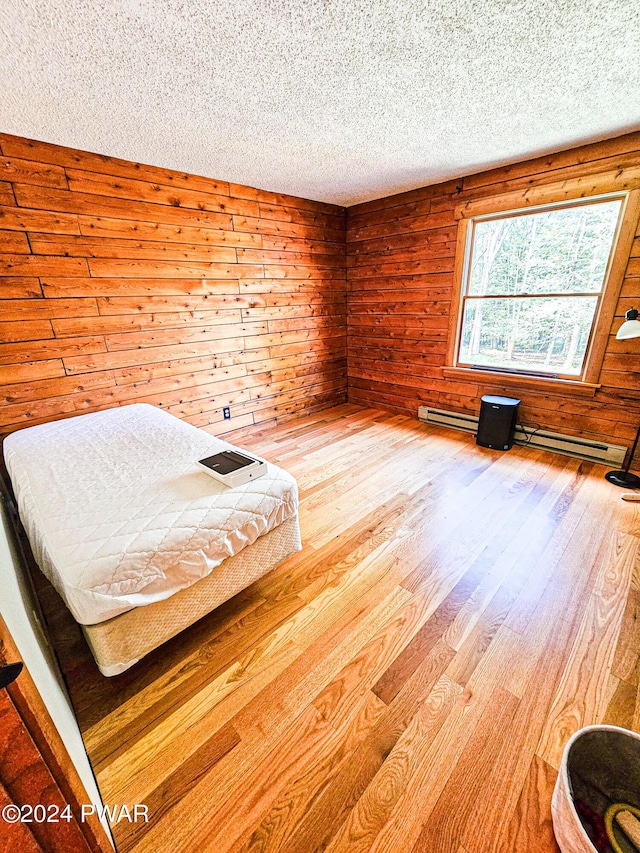 unfurnished bedroom featuring wood-type flooring, a textured ceiling, and wooden walls