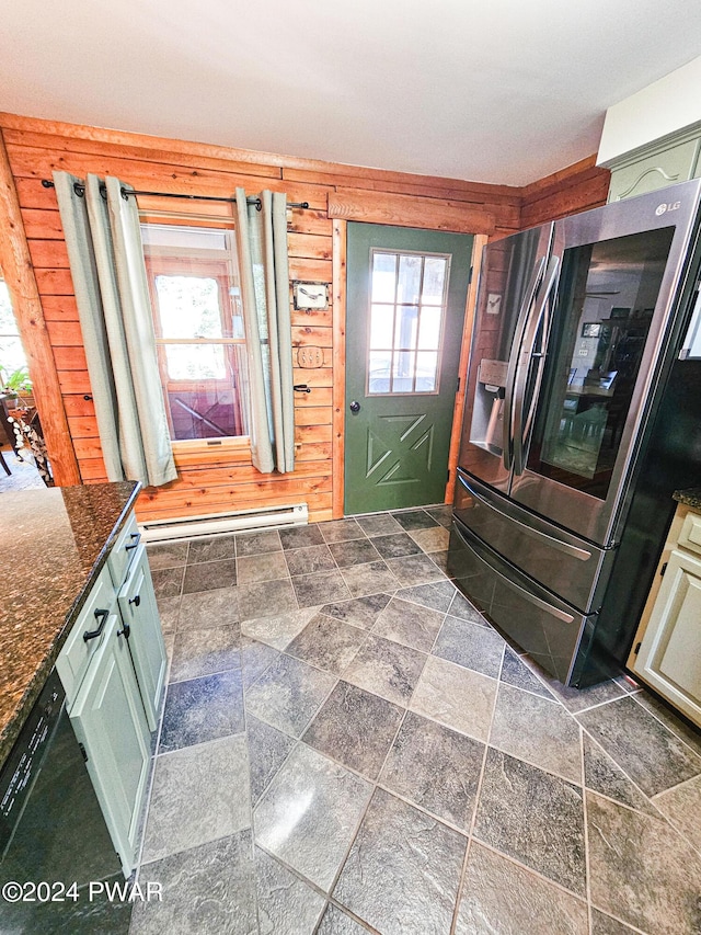 interior space with a wealth of natural light, stainless steel fridge, a baseboard radiator, and wood walls