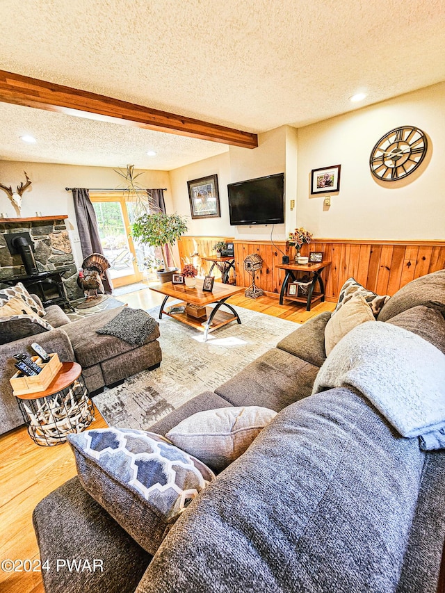 living room with beamed ceiling, hardwood / wood-style flooring, a textured ceiling, and wooden walls