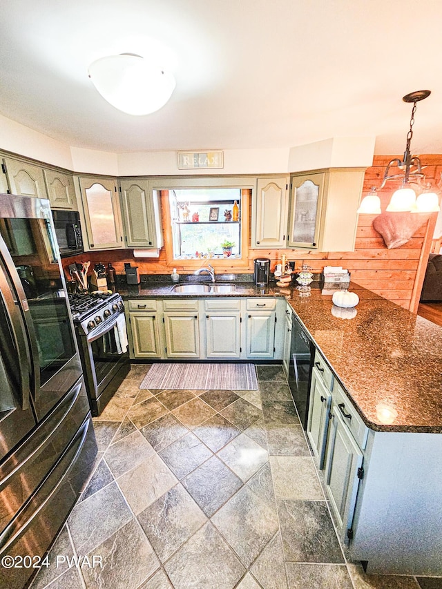 kitchen with refrigerator, dark stone counters, sink, pendant lighting, and stainless steel gas stove