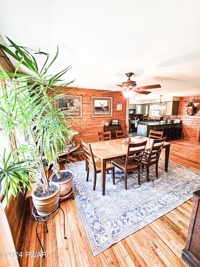 dining room with wooden walls, ceiling fan, and hardwood / wood-style flooring