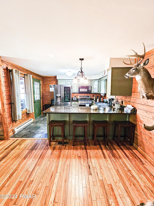 kitchen featuring appliances with stainless steel finishes, a baseboard radiator, light hardwood / wood-style flooring, and a breakfast bar area