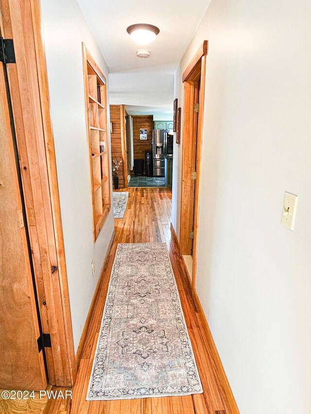 corridor with built in shelves and wood-type flooring