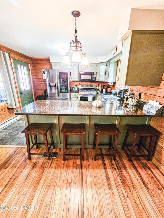 kitchen featuring kitchen peninsula, appliances with stainless steel finishes, light hardwood / wood-style floors, and a breakfast bar area