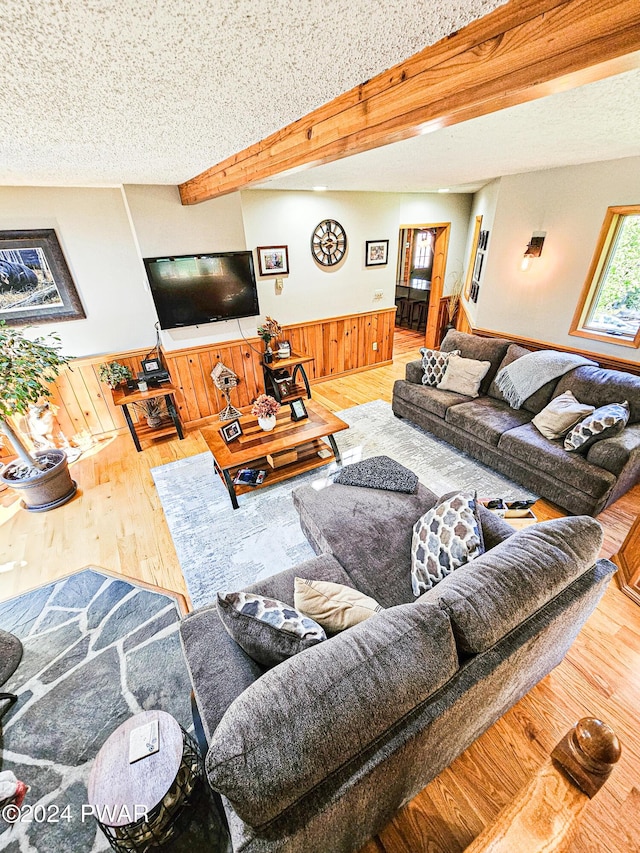 living room with hardwood / wood-style flooring, beam ceiling, a textured ceiling, and wooden walls