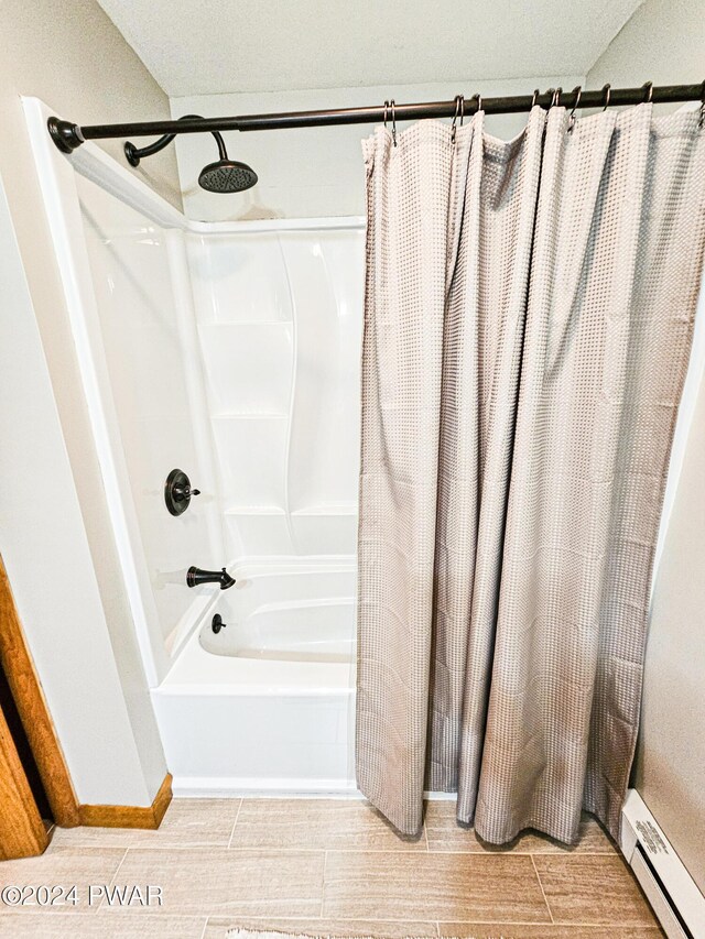 bathroom featuring shower / bathtub combination with curtain and baseboard heating