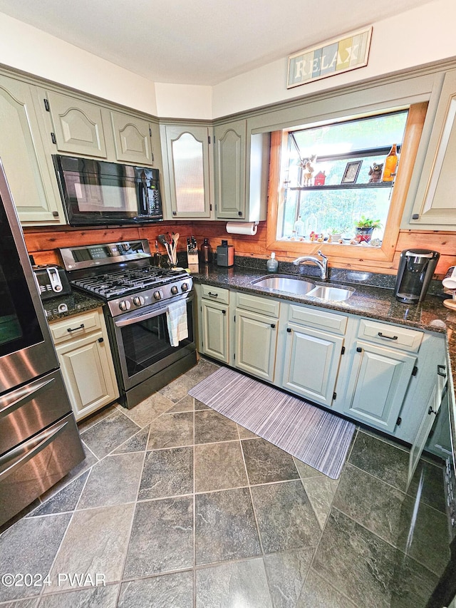 kitchen featuring dark stone countertops, sink, and stainless steel gas range