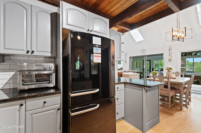 kitchen featuring pendant lighting, black fridge, light wood-type flooring, white cabinetry, and a chandelier