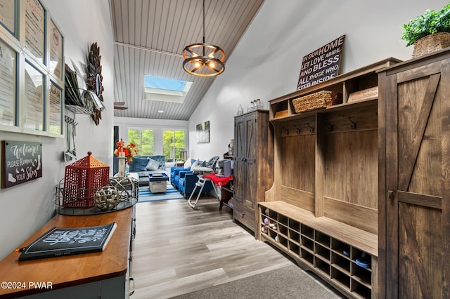 mudroom with a chandelier, light wood-type flooring, a skylight, and high vaulted ceiling